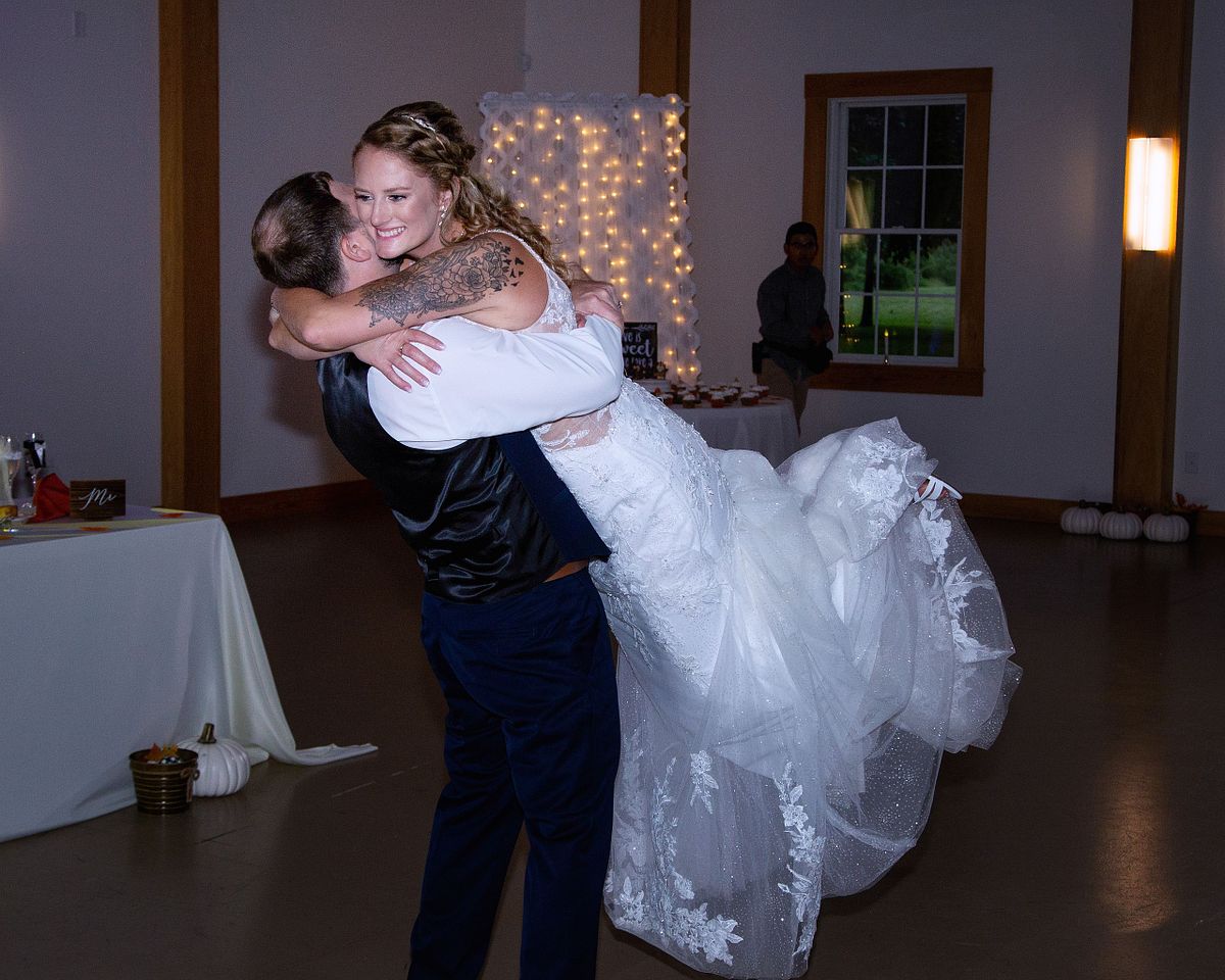 groom is lifting the bride during a dance with the bride smiling and glowing with happyness