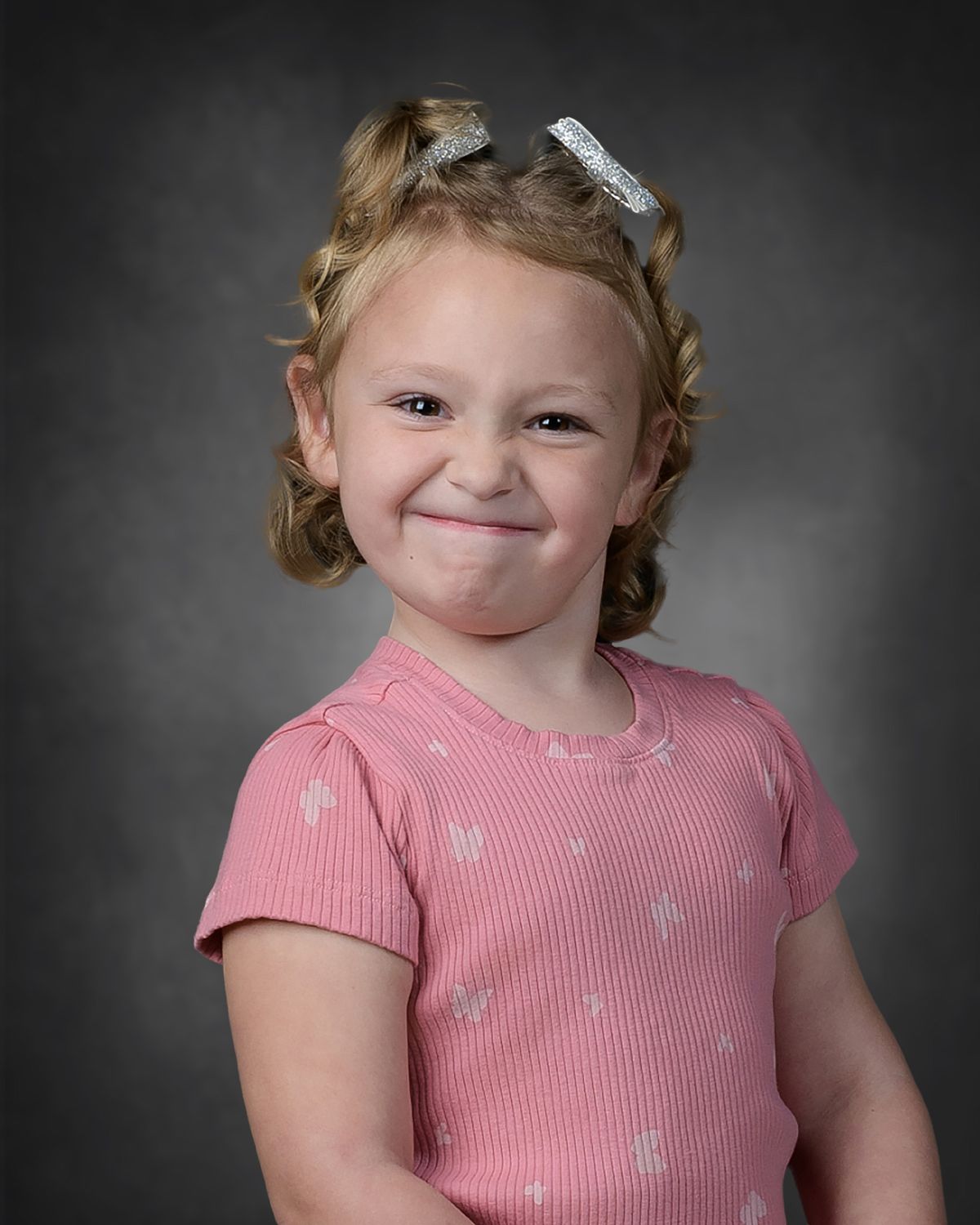 School photo of a Pre-K little girl making a face.