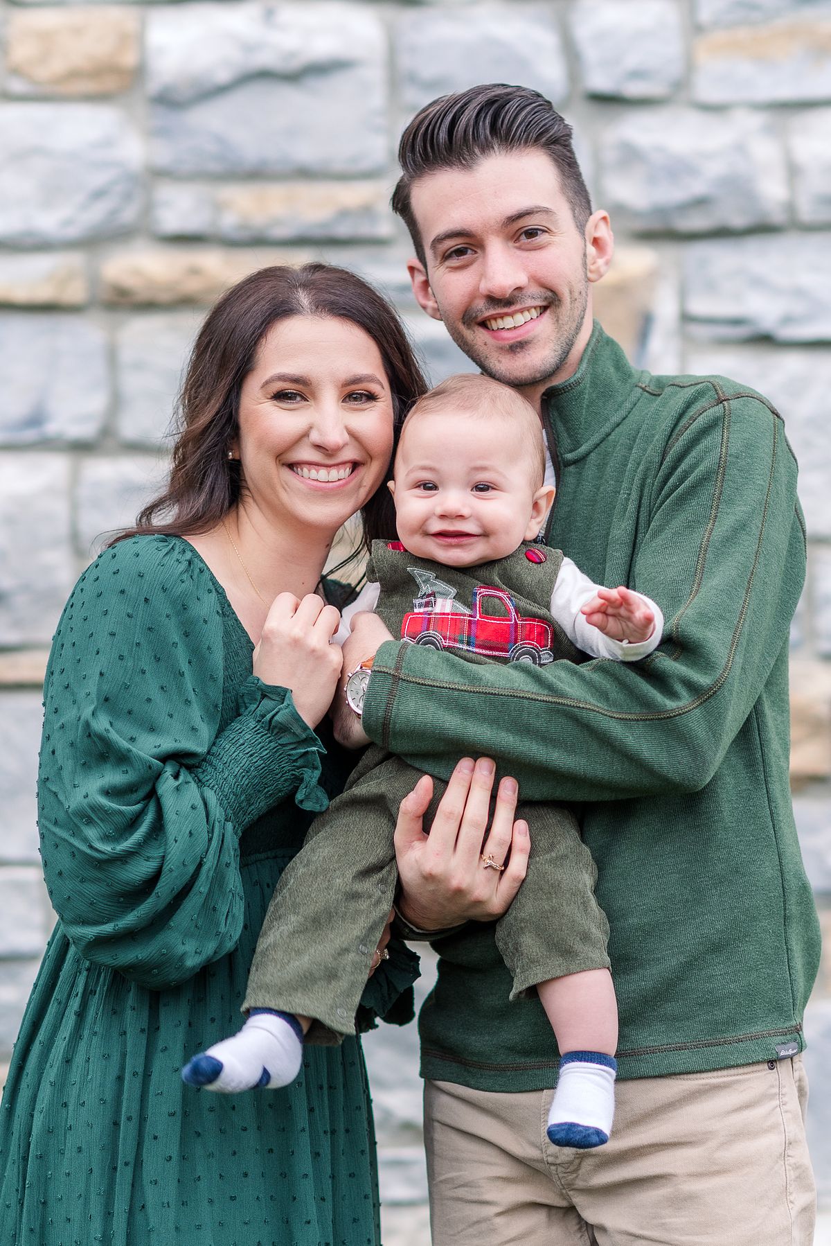 Husband and wife hold their baby and snuggle in close wearing Christmas attire with Cranberry Township, PA newborn photographer