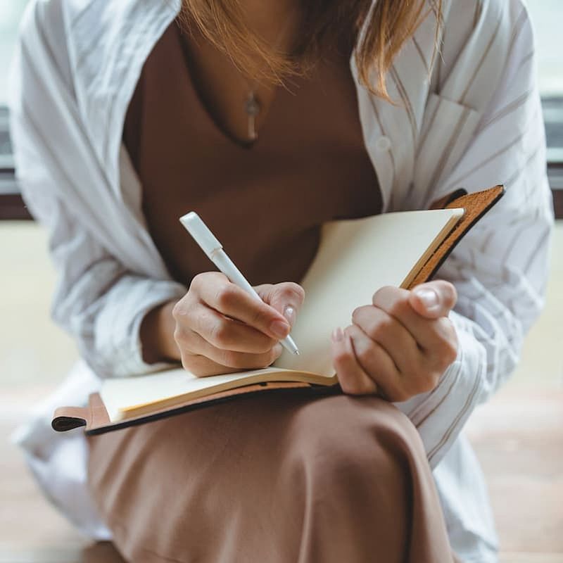 Woman writing in health journal or diary