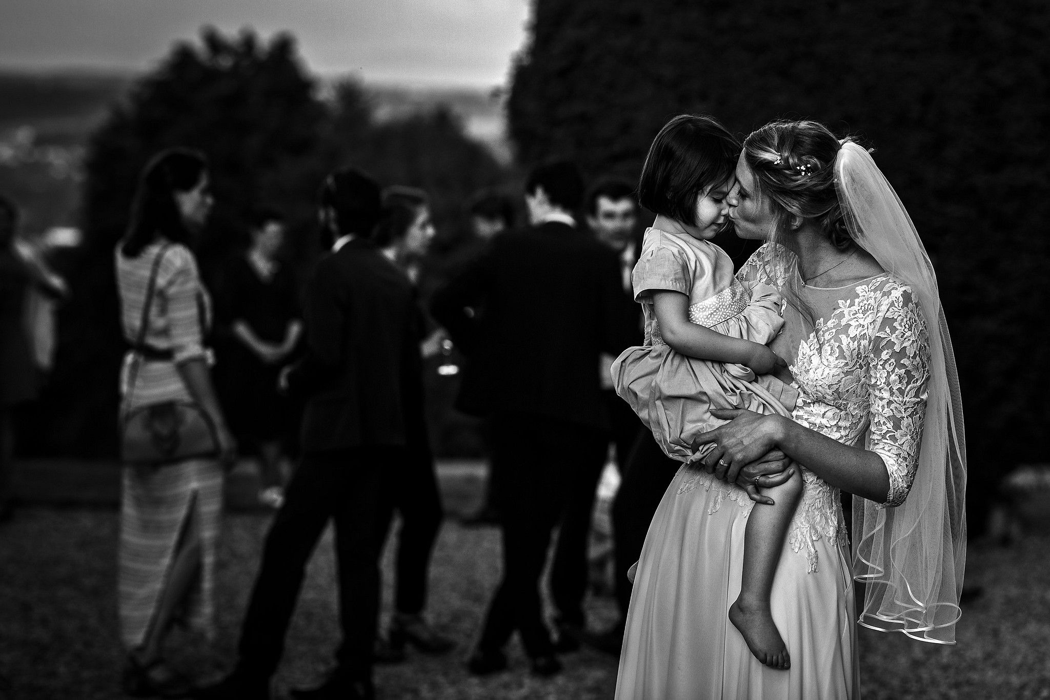 Mari&eacute;e qui tient une enfant dans ses bras et qui l'embrasse captur&eacute; par S&eacute;bastien CLAVEL photographe de Mariage &agrave; Lyon et Gen&egrave;ve