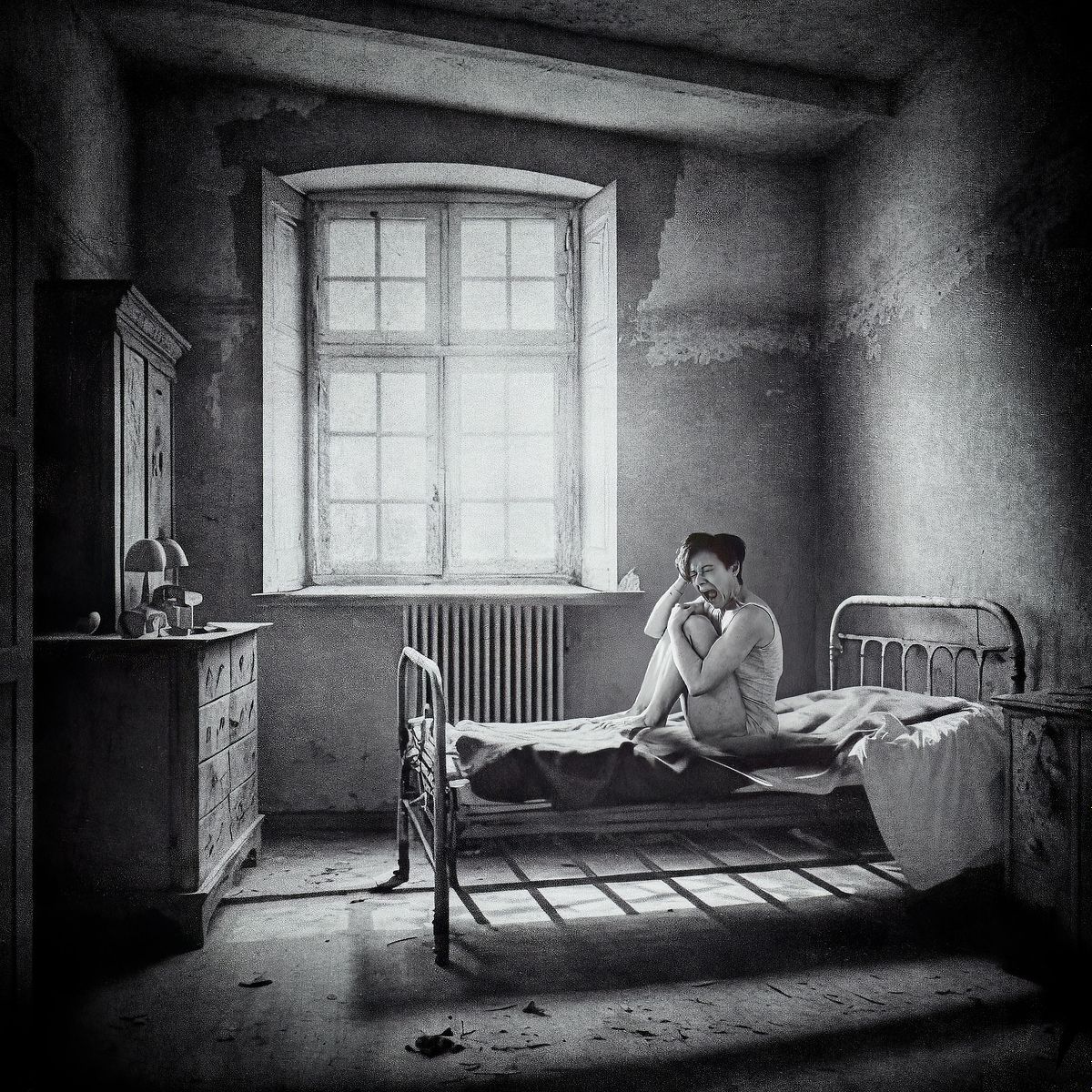 photo tarot The Asylum, femme en camisole hurlant dans une chambre sombre d&rsquo;asile ancien, &eacute;clair&eacute;e par une lumi&egrave;re crue