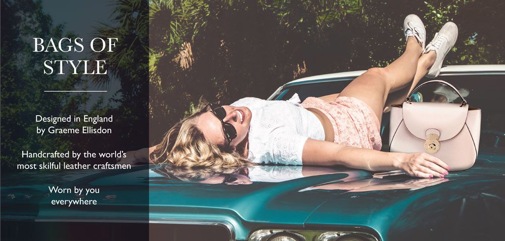 blonde woman laying on the bonnet of an American car with a pale pink bag next to her.