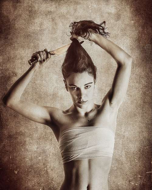 Portrait d'une femme compressant sa poitrine et se coupant les cheveux avec un couteau, exprimant la lutte identitaire et la dualit&eacute; de genre &mdash; photographie fine art par Pascal Yennis, Namur, Belgique.
