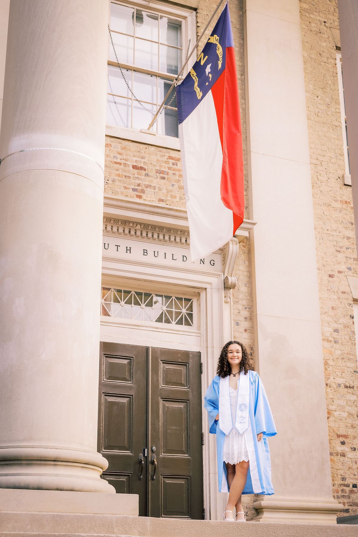 A woman in her graduation robe and stole on UNC's campus in Chapel Hill, NC