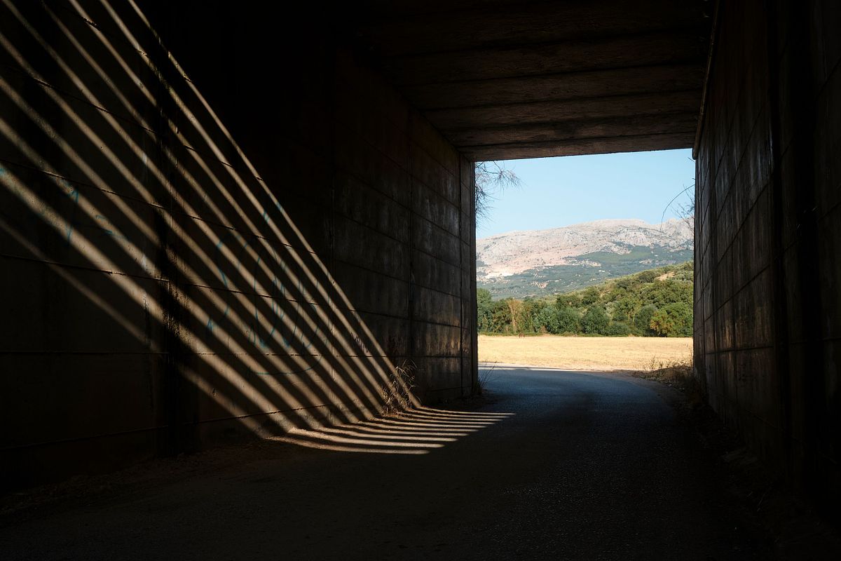 Light and shadows creating patterns inside a tunnel with a view of the Spanish countryside, captured by photographer Sandeep Gajula