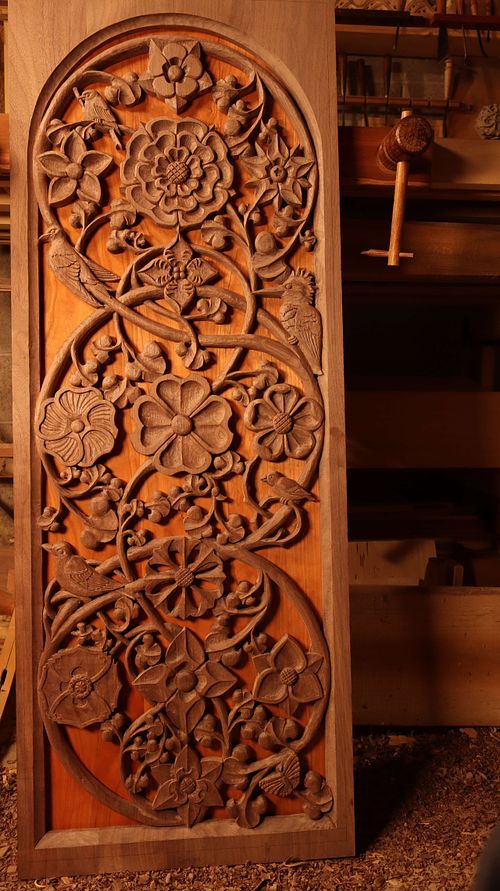 Highly carved door panel with rose, columbine, borage, begonia, gentian, poppy, dogwood, hollyhock, cornflower, virgin's bower, wild rose, and star of bethlehem flowers and a robin, goldfinch, purple martin, house finch, belted kingfisher, and butterfly carved into it.  For a large shrine being built to house a crucifix at St. Bernadette Catholic Church.