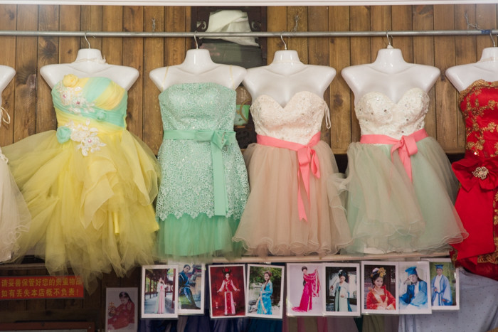 Brightly colored dresses in store window with old snapshots of women in dresses below