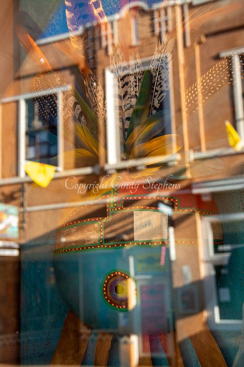 Sunset reflections on classic southwestern architecture with colorful native art featuring feathers in Santa Fe, New Mexico.