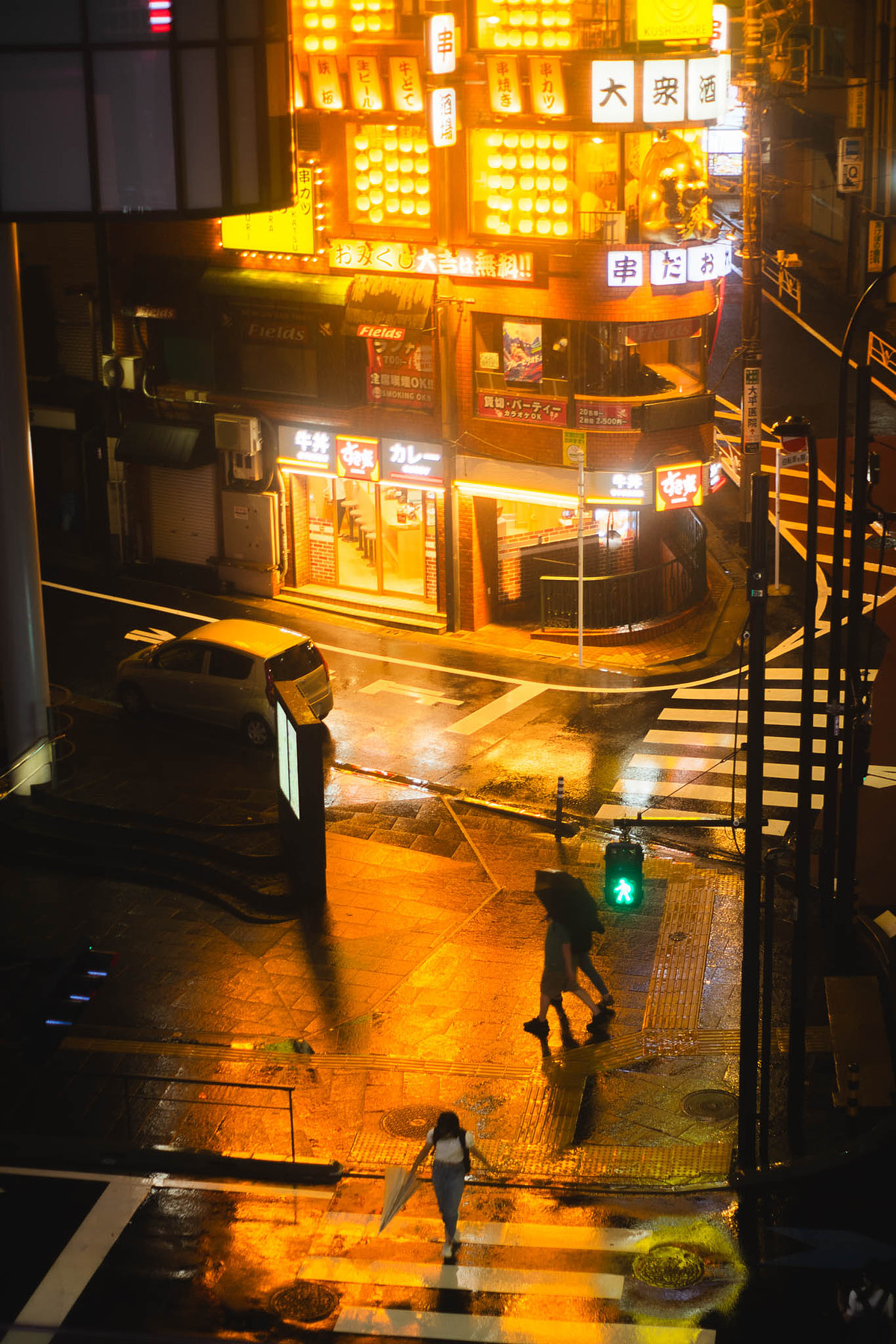 Carrefour de Shibuya vu d'en haut un soir de pluie, néons reflétés sur la chaussée