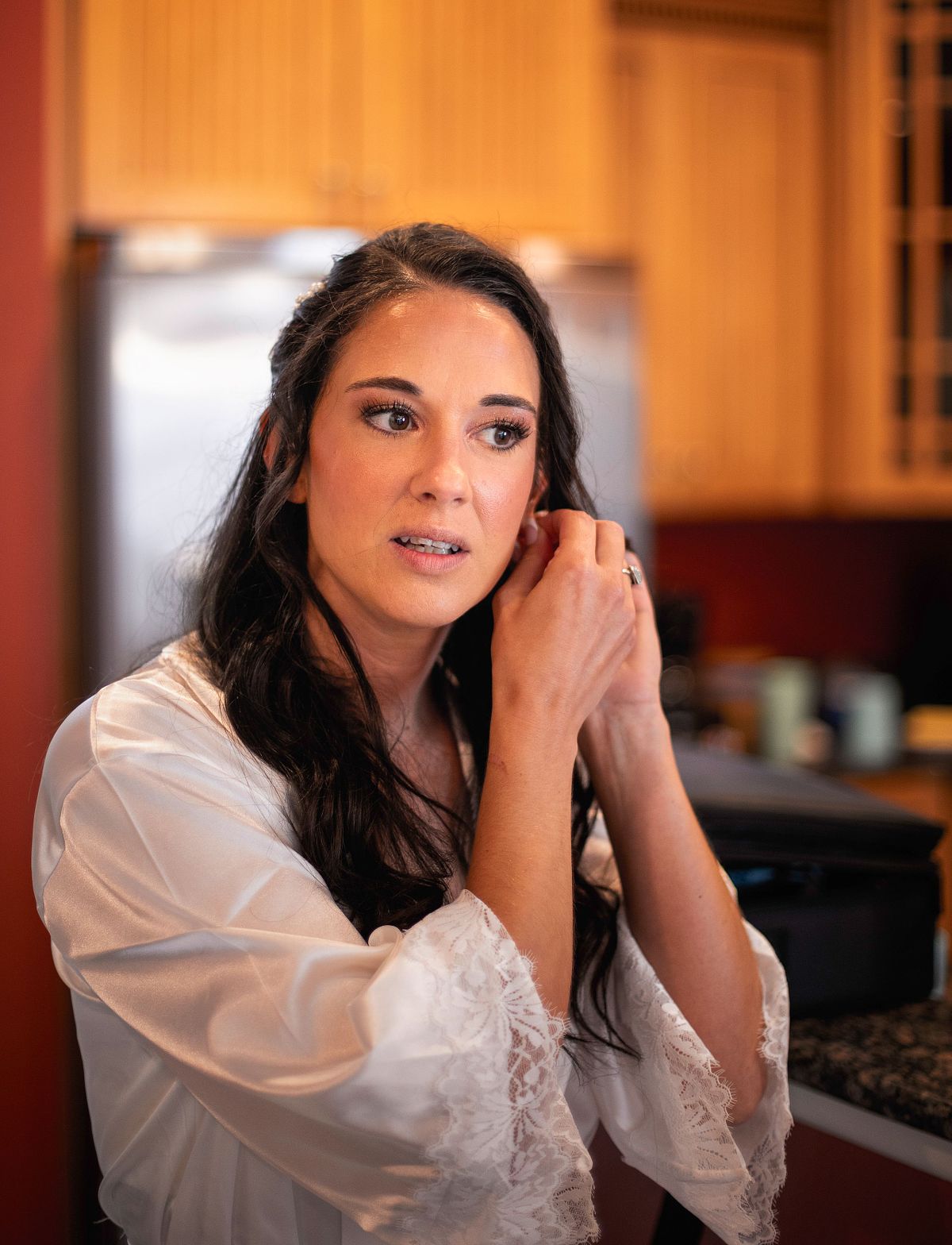 The bride is putting in her earings as she is getting ready before the ceremony on the Eastern Shore