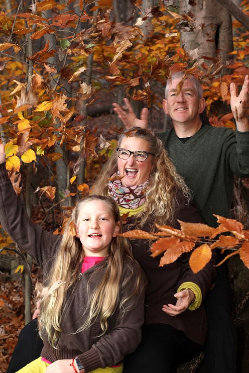 Family of three throws leaves up in the air