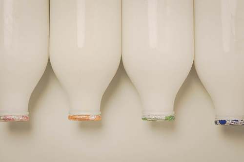 Glass milk bottles lined up in a row against a light background