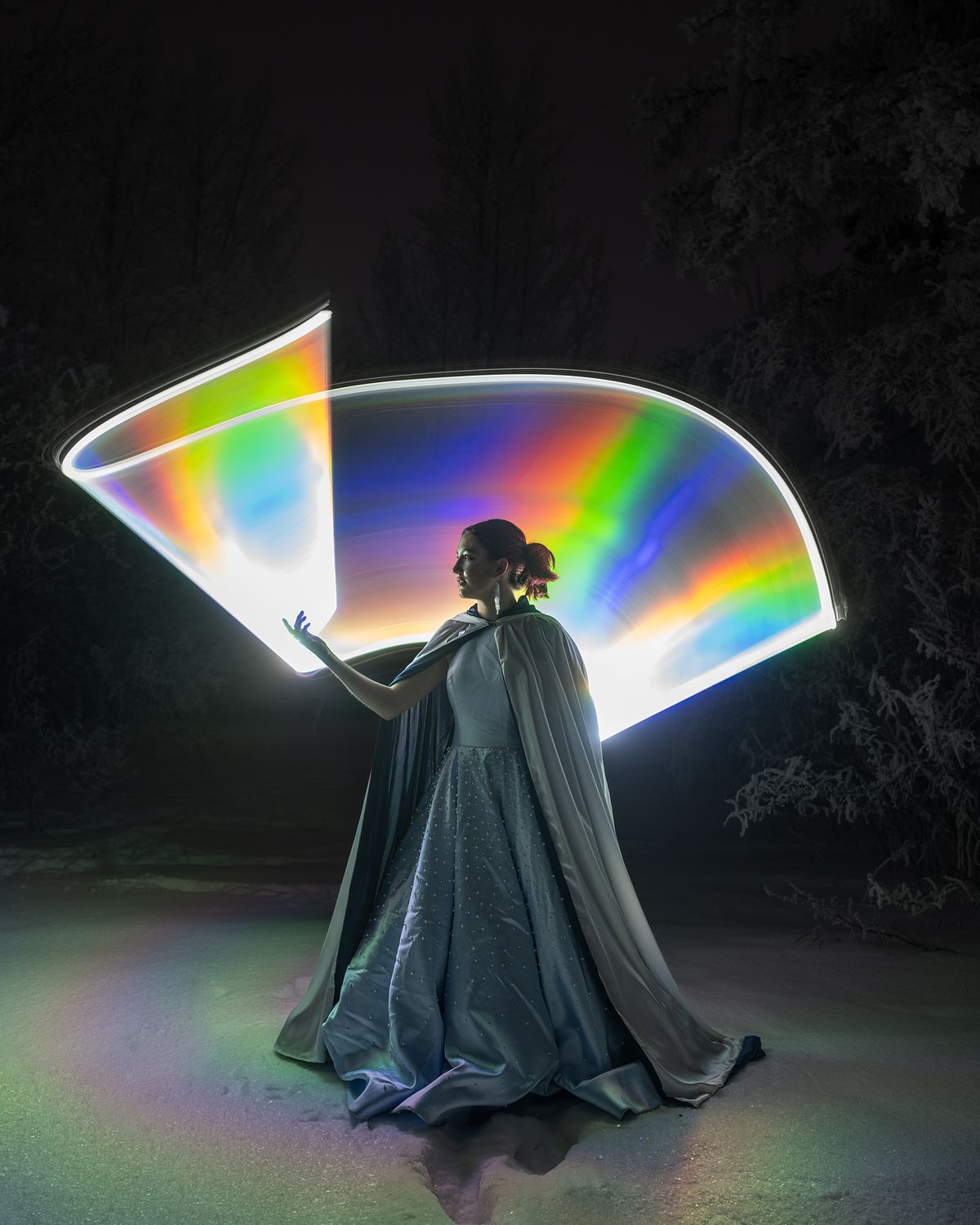 Cinderella standing in the snow wrapped with a rainbow of light.