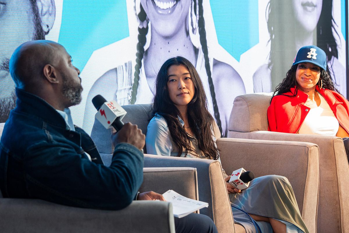 Three panelists engage in a lively discussion on stage at B.PHL Fest 2023 in Philadelphia, seated in armchairs with a vibrant mural-style backdrop behind them.