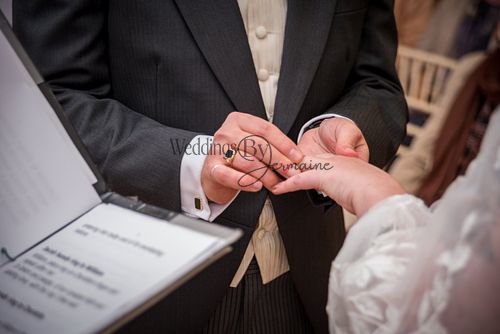 The groom placing the wedding ring on his bride's finger during the ceremony, captured by Weddings By Jermaine.