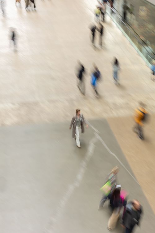 Människor i mjuk rörelse över stor betongyta sett uppifrån på museum