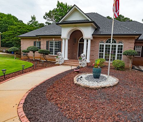 A beautifully landscaped front yard featuring a walkway and statues