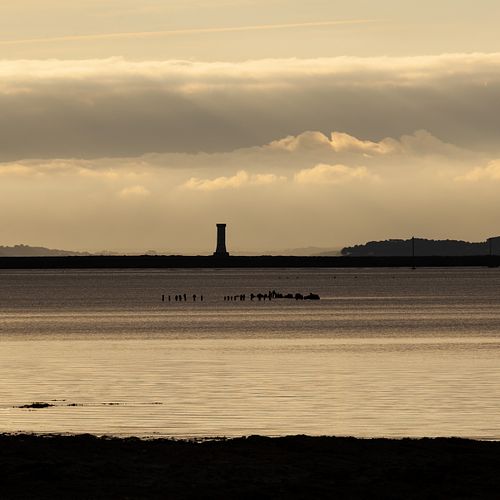 Phare isolé sur plan d’eau, ciel de fin de jour.