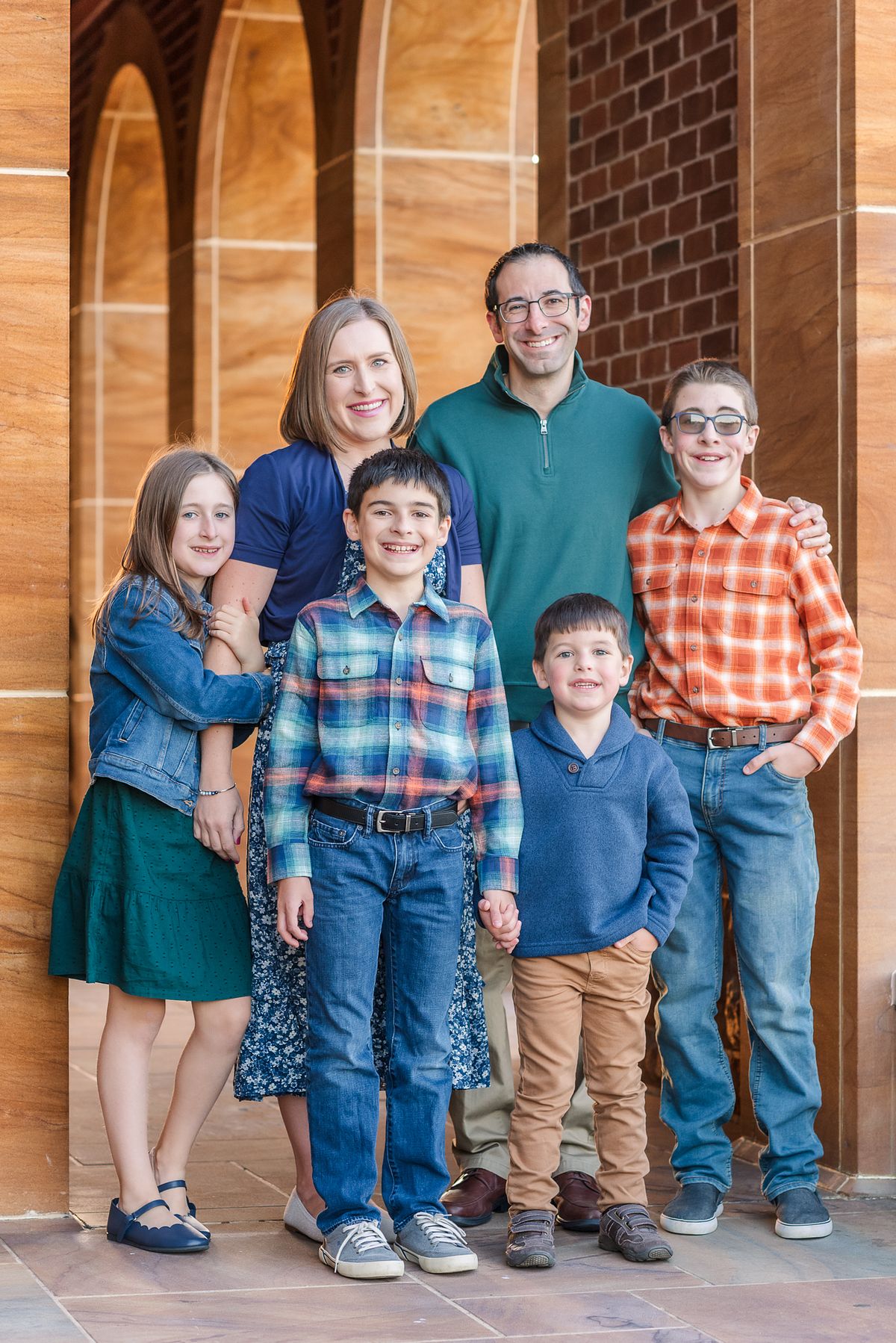 Family of six standing in arches of Wexford Saints John & Paul Church in golden hour light with a Cranberry Township, PA newborn photographer