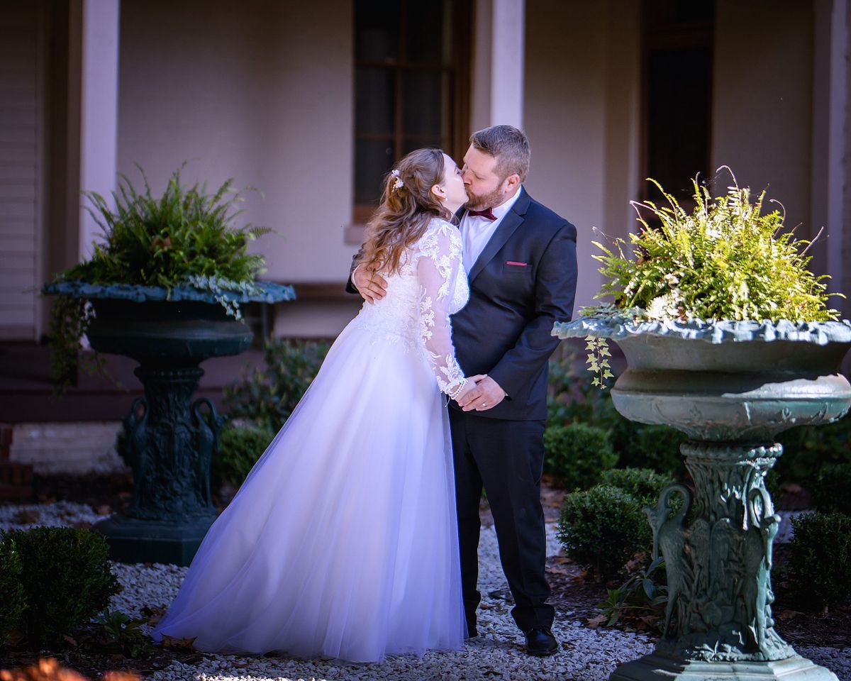 bride kissing groom at the historic ross mansion victorian wedding venue with back porch in background