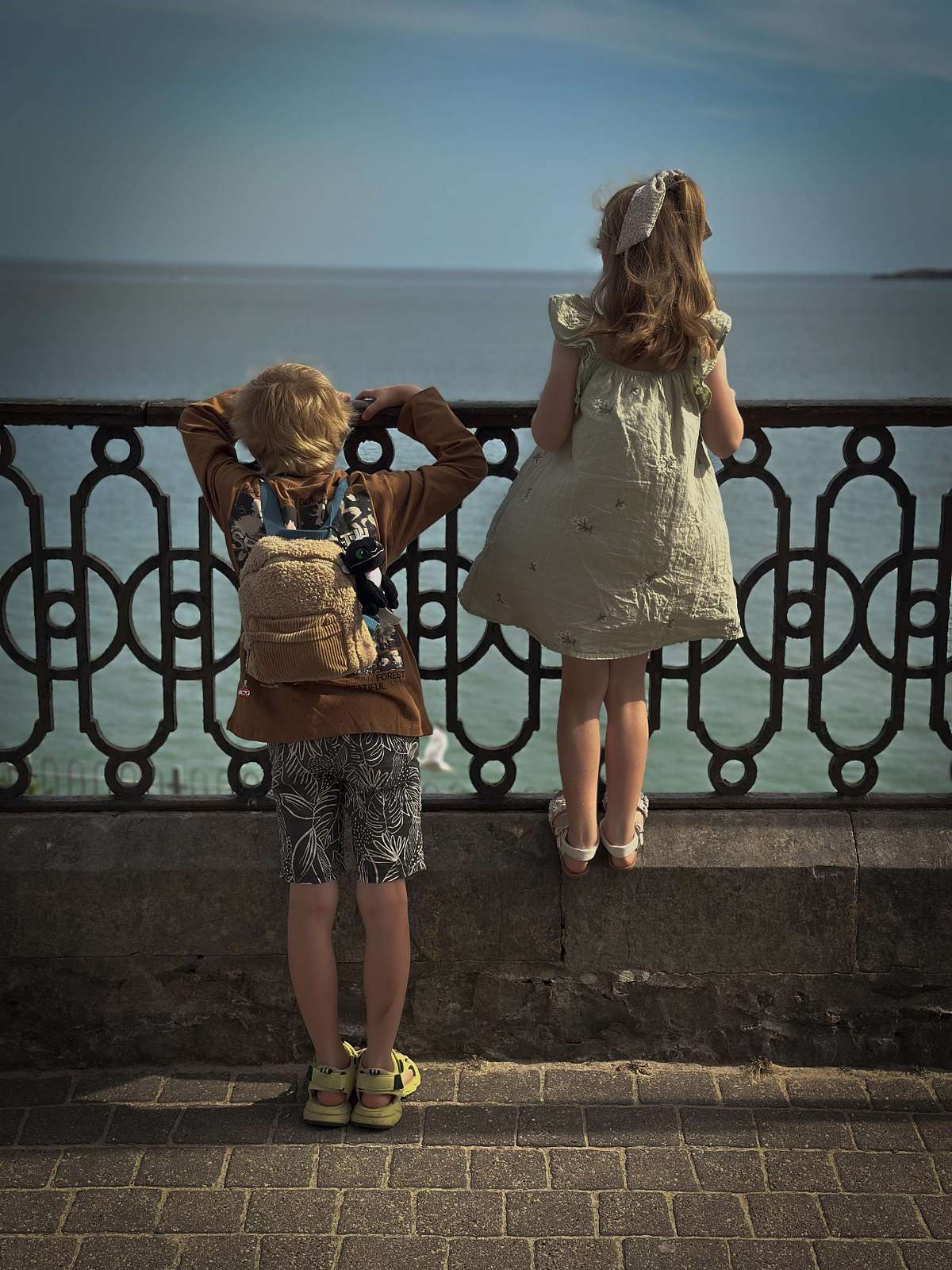 Two children standing at ornate iron balcony railing, lifestyle childrenswear photography UK