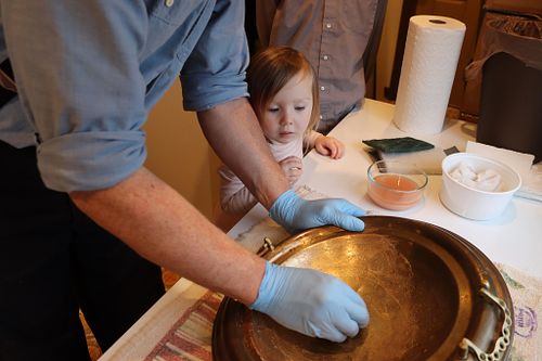 Wes Baker polishes the antique baptismal font bowl while his daughter looks on