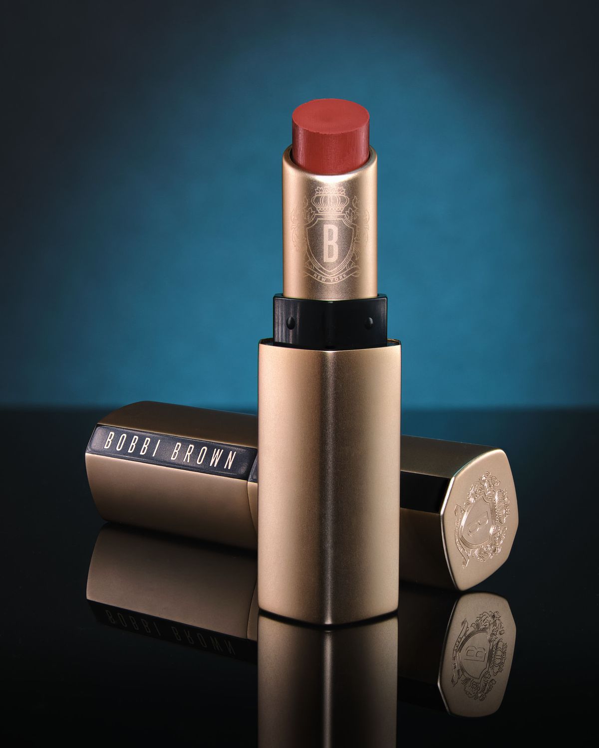 Two gold lipstick tubes on a reflective back base with blue backlighting.
