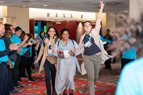 Attendees are greeted with applause and excitement during the high-energy tunnel welcome at Grace Hopper Celebration 2024 in Philadelphia.