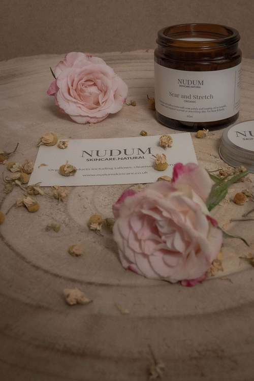 Glass jar product styled with soft pink roses on a neutral surface