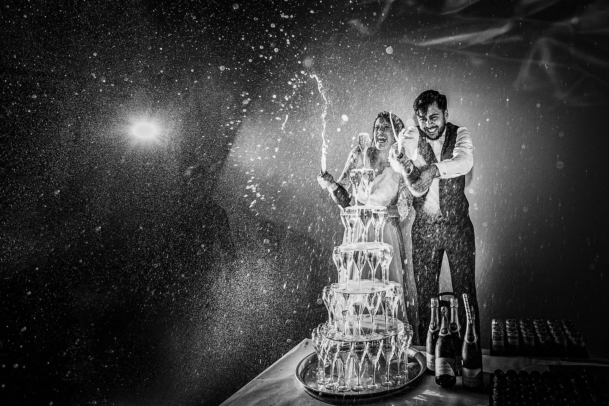Couple de mari&eacute;s qui aspergent leurs invit&eacute;s avec du champagne pendant le gateau captur&eacute; par S&eacute;bastien CLAVEL photographe de Mariage &agrave; Lyon et Gen&egrave;ve