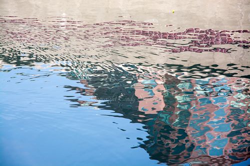 A building shimmers in water creating impressionistic pink shapes and forms