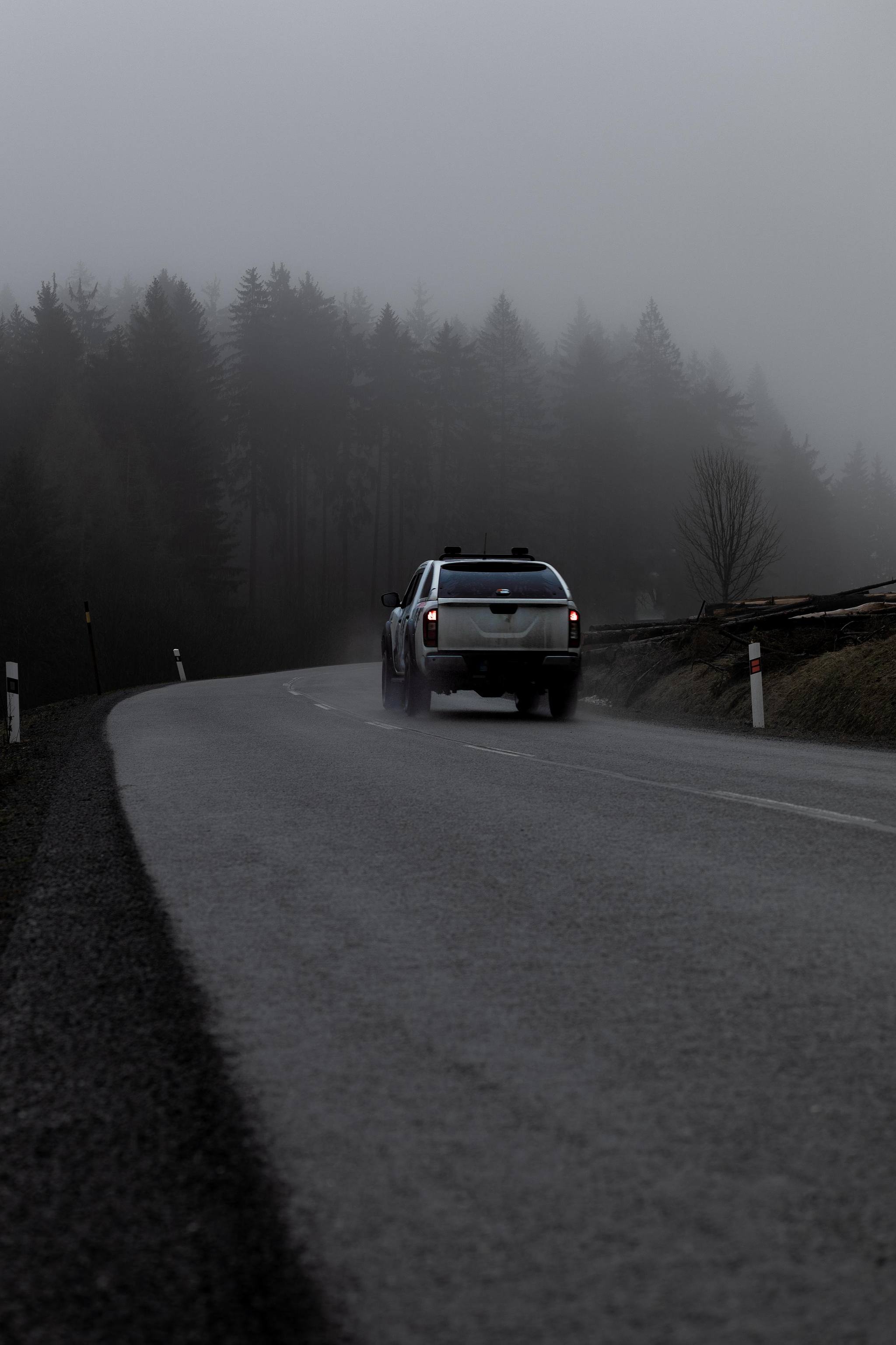 Route humide avec véhicule, brume au fond.