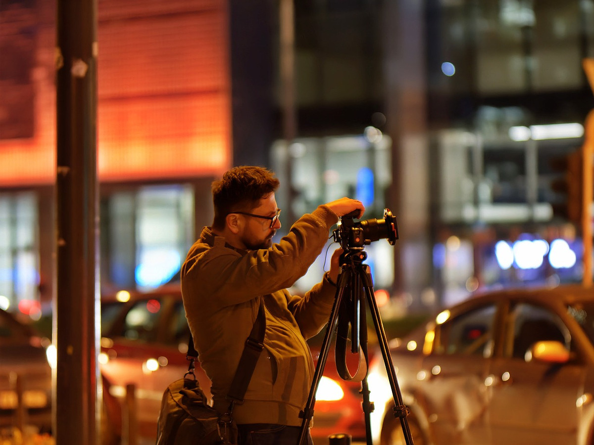 Professional street photographer capturing urban images at night.
