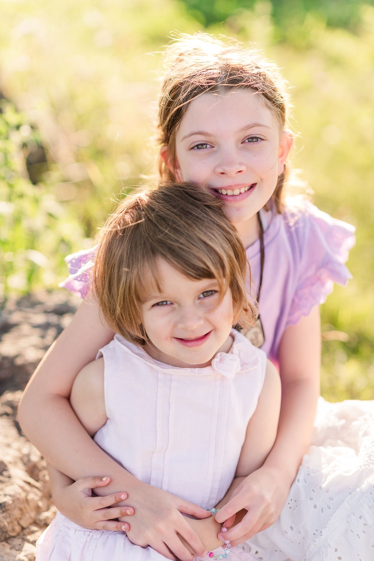 Two sisters hugging and smiling in summer sunset light at Cranberry Township Community Park