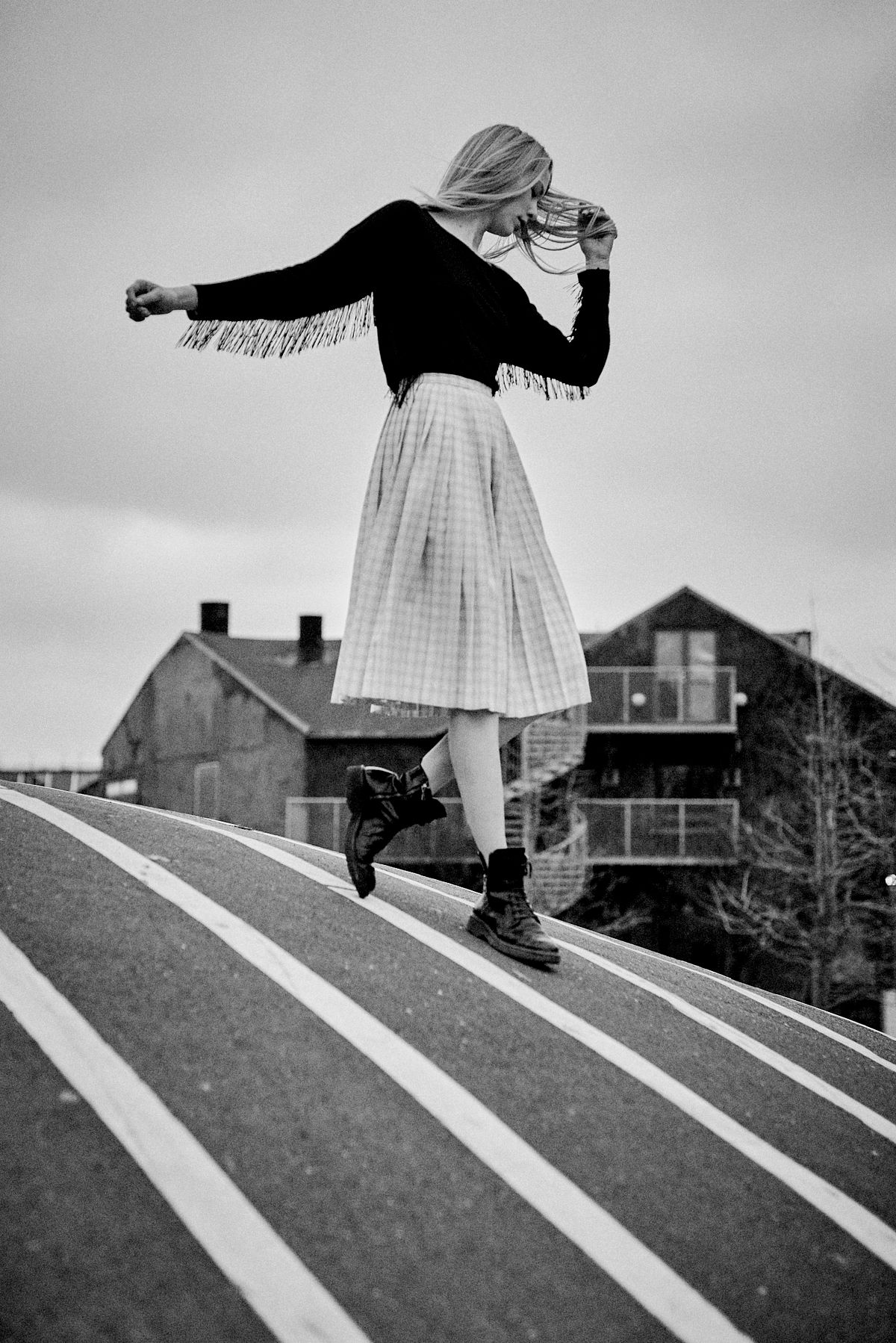 cinematic black & white photography of a woman in movement dancing and holding her head over a striped bike lines. Shot by Gabriel Matula in a poetic way.