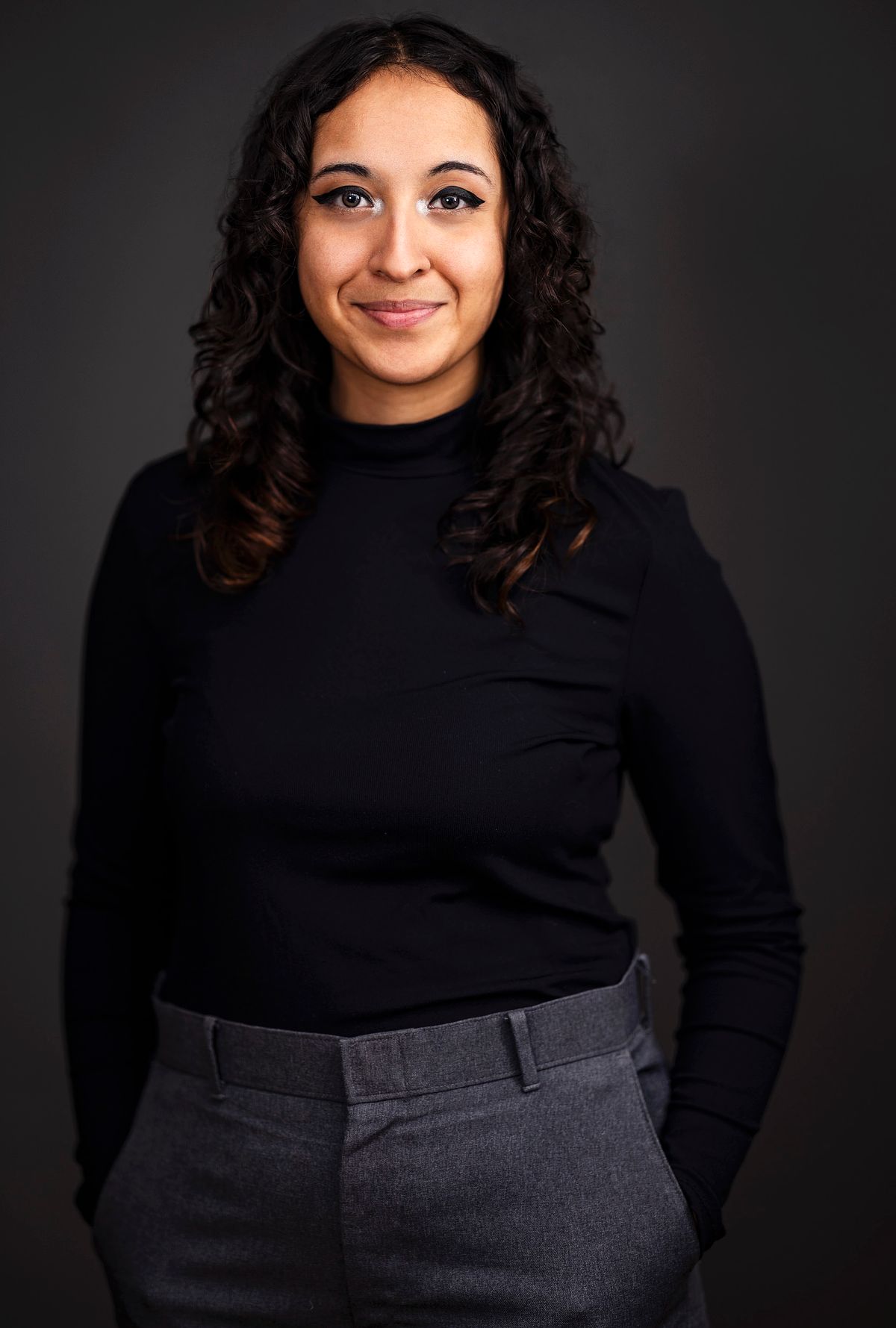 Corporate headshot of a woman wearing all black against a black background.