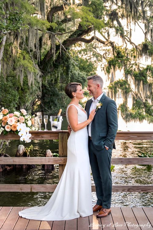 An elegant mature bride and groom embracing and smiling during their second marriage portrait session in a scenic Florida outdoor setting.