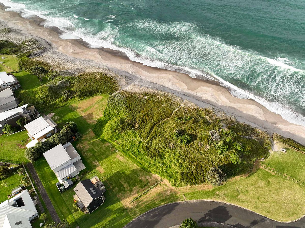 Aerial drone view of a premium beachfront property and Whiritoa Beach coastline by Flax Cove Studio.