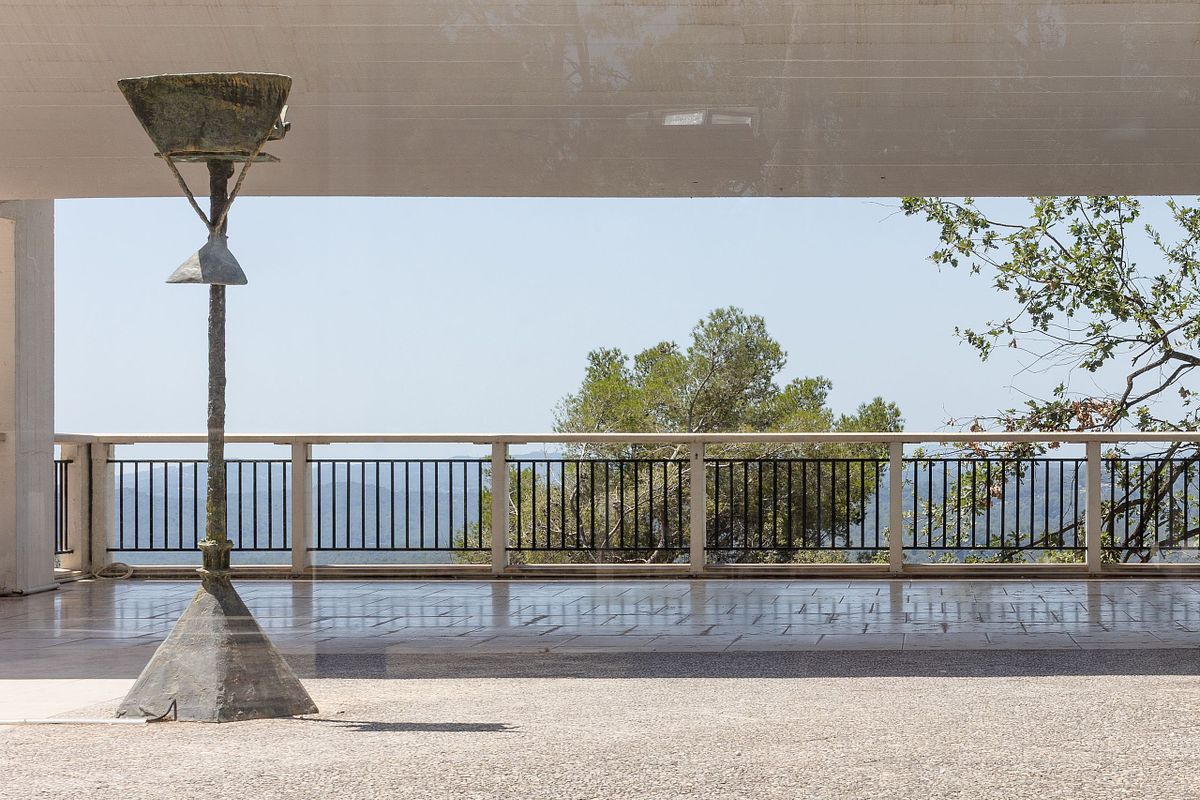 &Ouml;ppen modernistisk terrass med skulptur och utsikt &ouml;ver landskap, fotograferad i naturligt ljus.