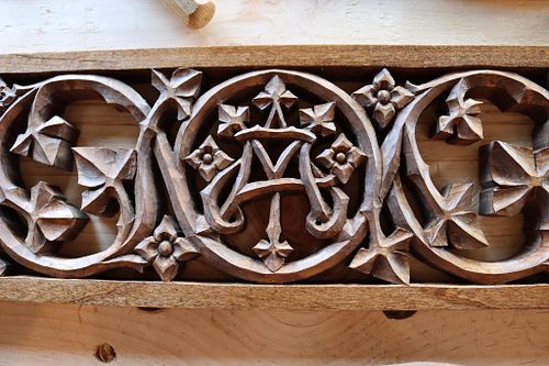 detail of Marian monogram carving and scrolling vines and flowers