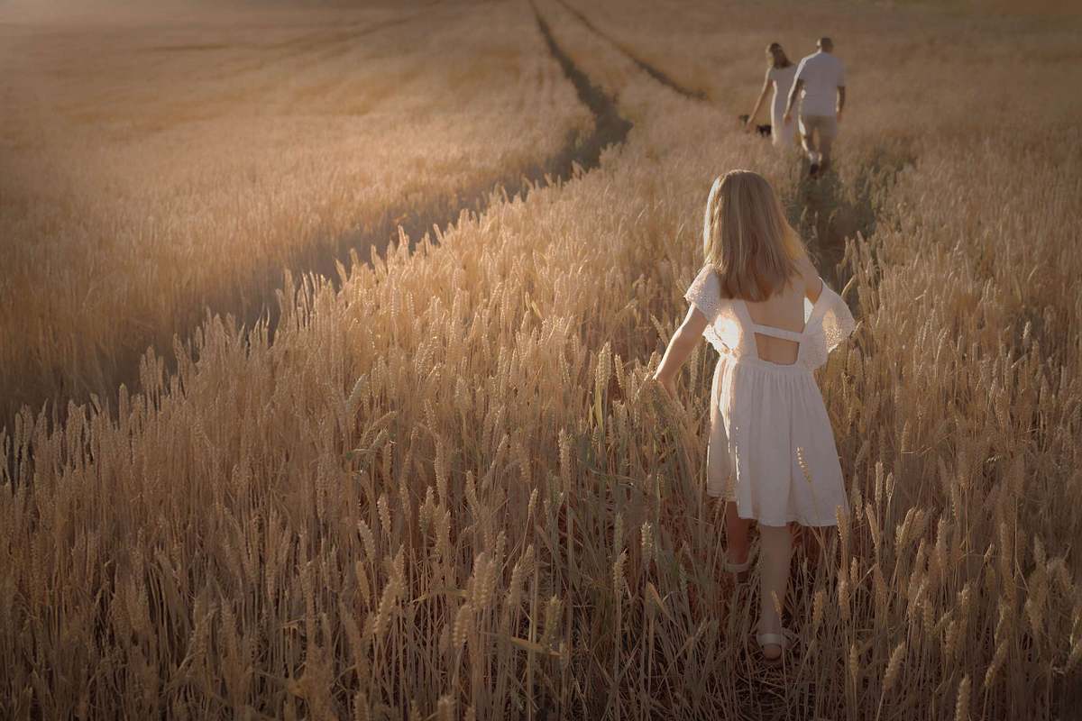 Girl in white dress walking through wheat field, children's campaign photography Northamptonshire UK