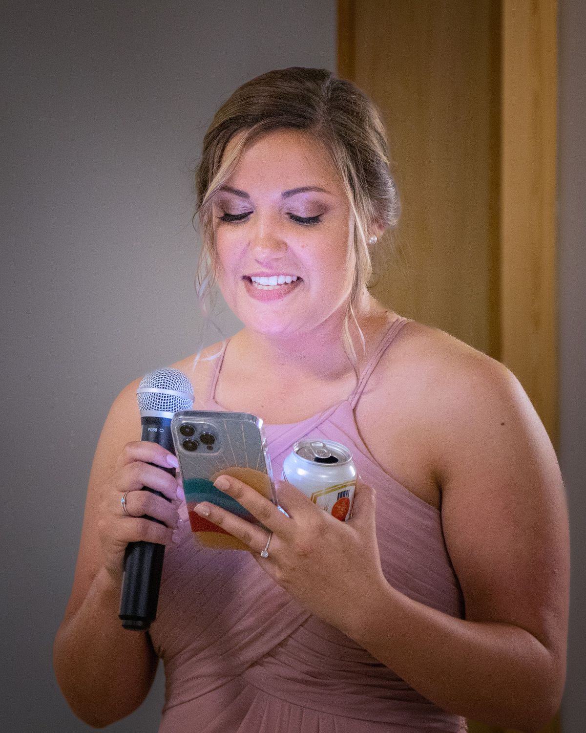 maid of honor reading her speech of the phone during reception while holding a beer in her hand