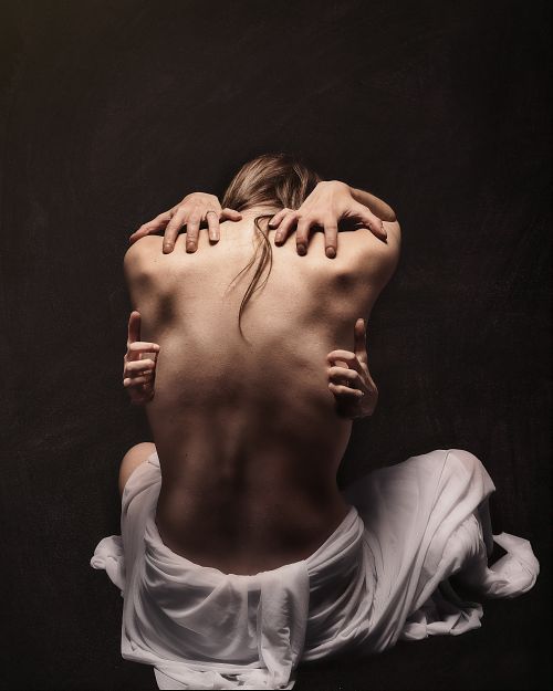 Photographie fine art d’une femme nue vue de dos, retenue par quatre mains métaphoriques, symbolisant un conflit intérieur intense, des luttes mentales et émotionnelles — œuvre de Pascal Yennis, Namur, Belgique.