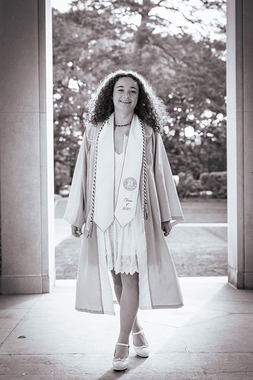 A woman in her graduation robe and stole at the Bell Tower on UNC's campus in Chapel Hill, NC