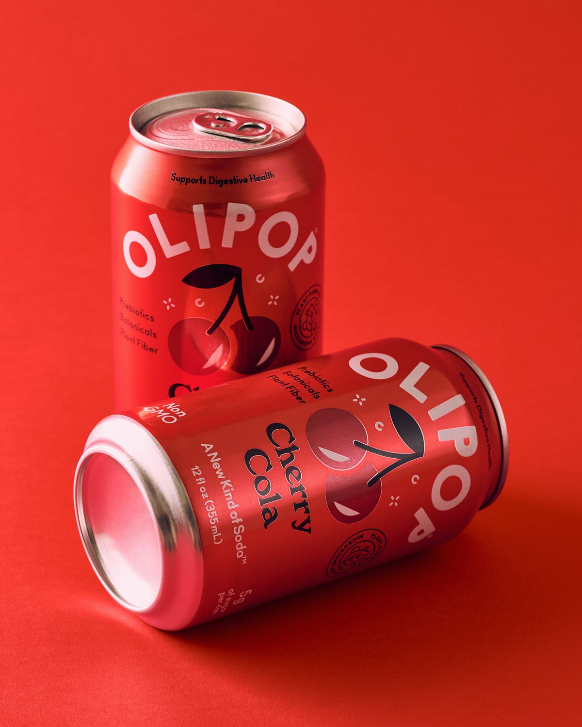 Two cherry cola cans on a red seamless backdrop