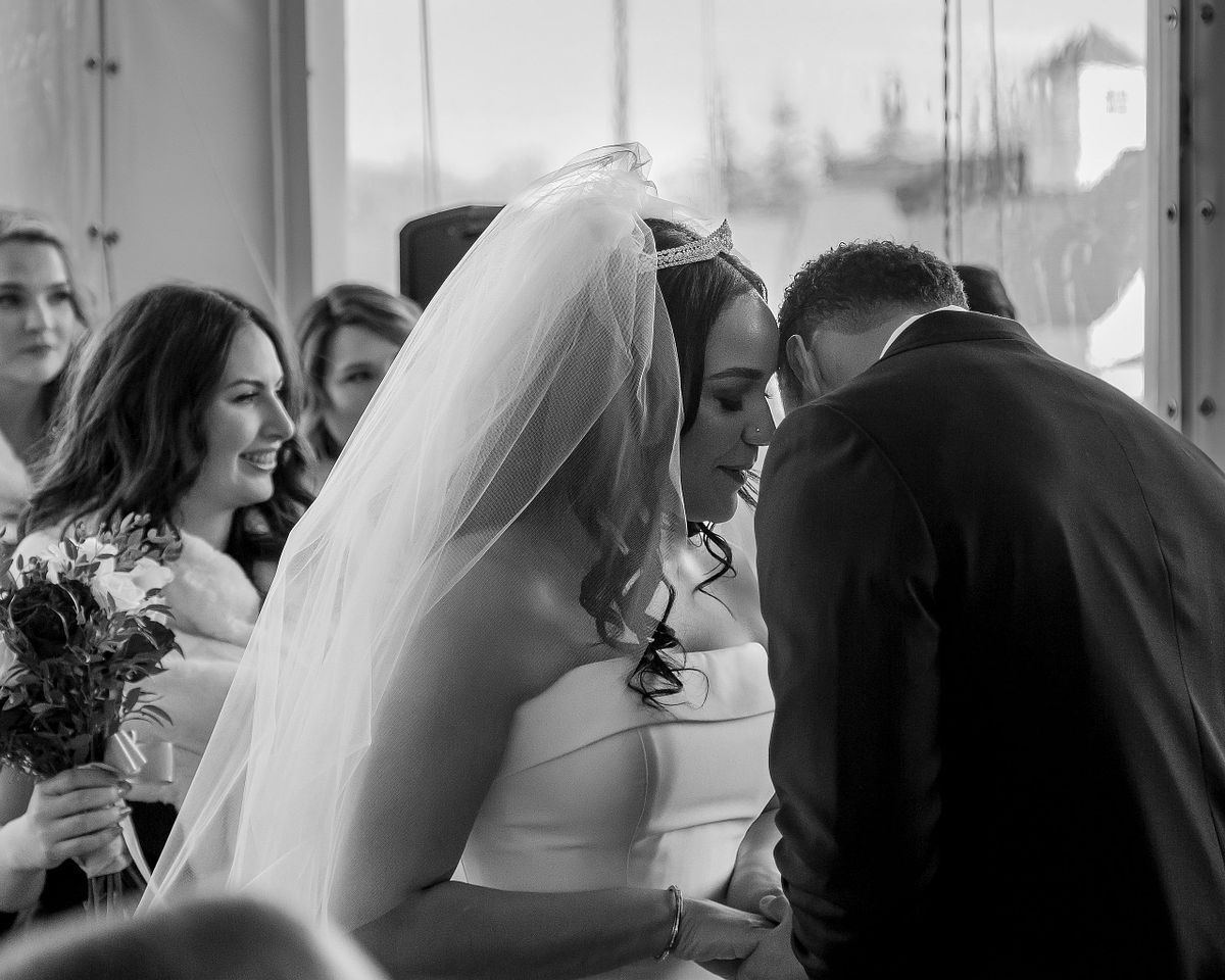 black and white of the bride whispering to the groom during the ceremony