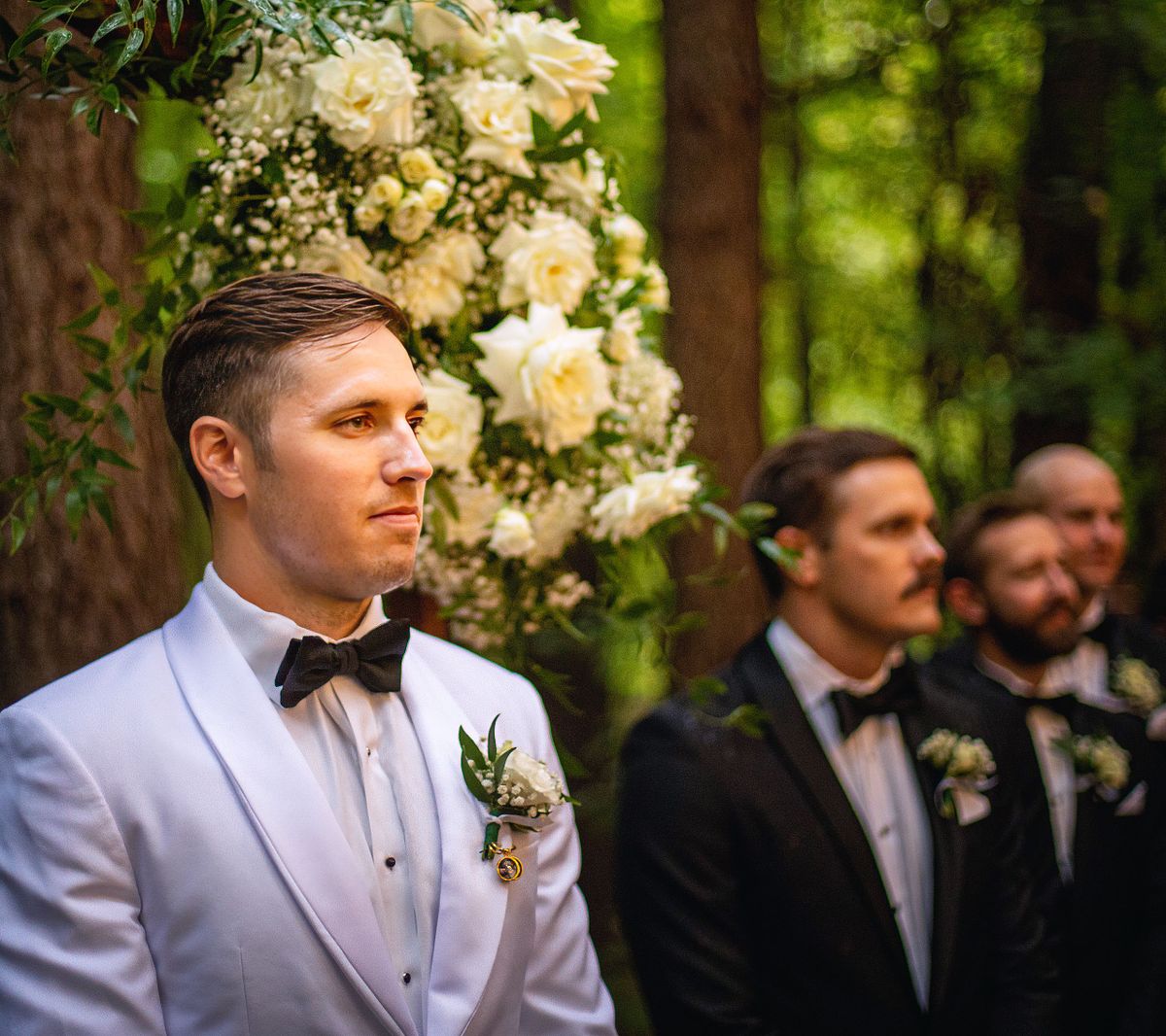 an emotional groom waiting in the woodlands of kylan barn, his groomsmen are to the side of him