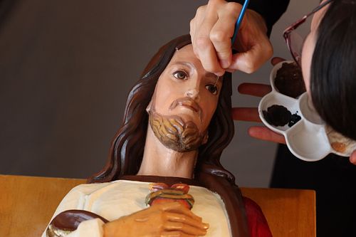 Kelly Baker painting the antique statue's face
