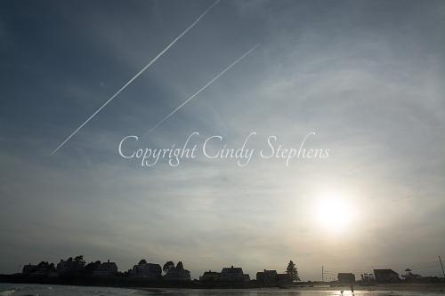 Individuals on a beach at twilight framed by a beautiful sky